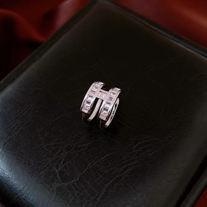 Macro shot of silver H-shaped ear cuff with baguette zircons on black leather