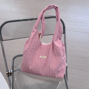Detailed shot of pink pleated fabric tote bag with brand label on a stylish chair