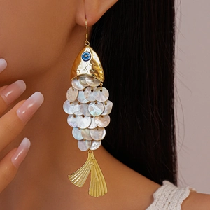 Close-up of golden fish earrings with shell scales and blue eye on female model