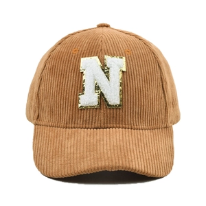 Detailierte Textur der braunen Cord-Baseballkappe mit Chenille-N-Patch und Goldpailletten