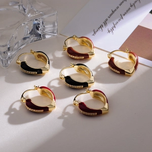 Detail of vintage French gold earrings with red and black enamel drip and zircon accents