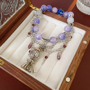 Detailed macro view of purple crystal beads, hollow metal ball and tassel on the bracelet