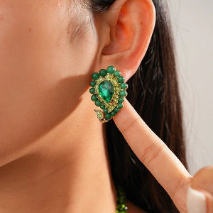 Close-up of a vintage bohemian earring featuring a pear-shaped emerald crystal and green beads
