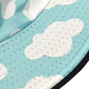 Detailed shot of double-sided sun hat with light blue sky and white cloud print patterns