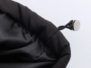 Detail of adjustable drawstring hem with metallic toggle on black oversized puffer coat