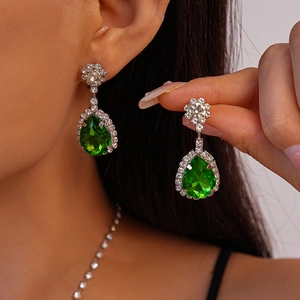 Détail de boucles d'oreilles poires en émeraude avec sertissage de cristaux blancs