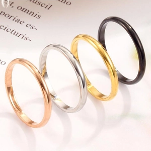 Detailed view of four minimalist 18K gold-plated rings in rose, silver, gold, and black