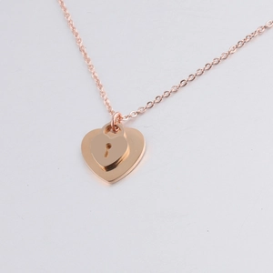 Close-up of rose gold heart pendant with lock hole design on a fine metal chain