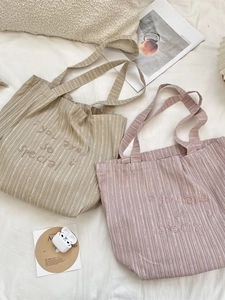 Striped canvas tote bags with smile embroidery in beige and pink on white bedding