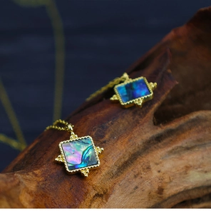 Macro detail of vintage square abalone shell pendants with 18K gold plated borders