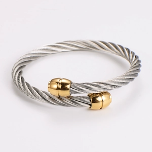 Detail of twisted cable steel wire bracelet with gold plated ball ends and silver rope texture