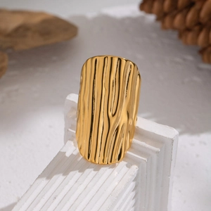 Statement gold-plated wave textured wide open ring on a fluted marble pedestal