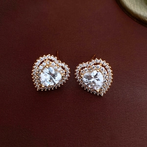 Close-up of golden heart earrings with sparkling double halo cubic zirconia crystals