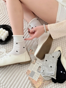 Detail of white, gray, and black polka dot cotton socks with ribbed non-slip cuffs
