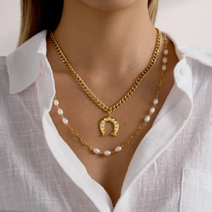Close-up of layered gold horseshoe necklace with cubic zirconia and delicate pearl chain