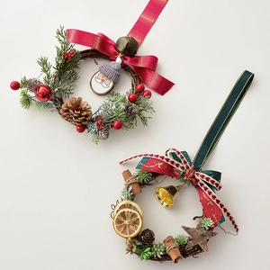 Mini Christmas wreaths with pine cones, red berries and bells on white background