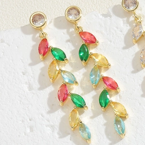 Macro shot of colorful marquise gemstones on gold-plated leaf-shaped dangle earrings