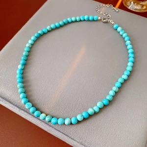 Detailed view of natural turquoise beaded necklace with silver clasp on velvet display