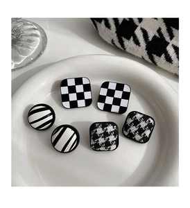Detail of checkered and houndstooth pattern earrings displayed on a white ceramic plate