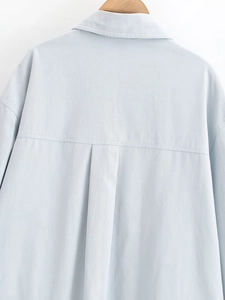 Detailed back view of light blue cotton denim shirt showing yoke and pleat texture