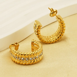Detailed view of gold-plated twisted C-hoop earrings with clear rhinestone inlay