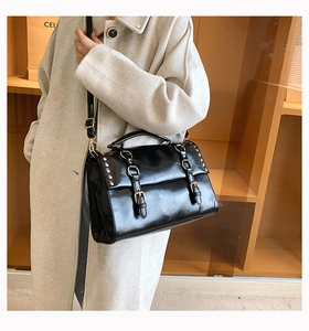 British style black PU leather satchel bag with buckle straps worn by a model