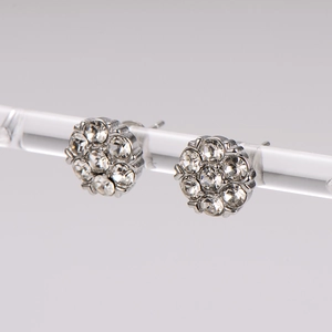 Elegant silver flower stud earrings with sparkling rhinestones on a display stand