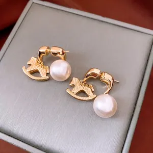 Vintage gold rocking horse earrings with pearls on red silk background