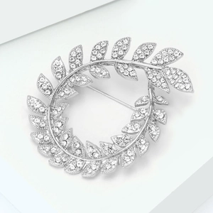 Detail of silver olive branch brooch with sparkling rhinestones on a white pedestal