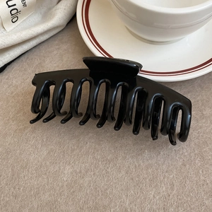 Detailed close-up of a glossy black square hair claw clip on a minimalist gray background