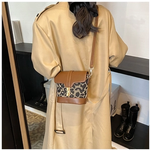 Detail view of stylish leopard print bucket bag with metal buckle and brown leather