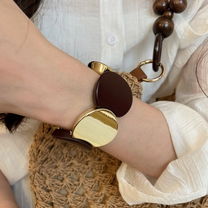 Close-up of chunky acrylic and gold metal stretch bracelet with vintage oval elements