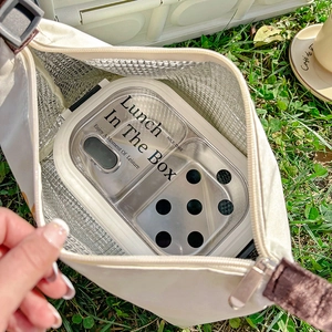 White insulated lunch bag with aluminum foil lining shown on grass with lunch box