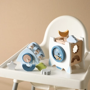 Detail of wooden rocket activity toy with shape sorting holes on a white high chair tray