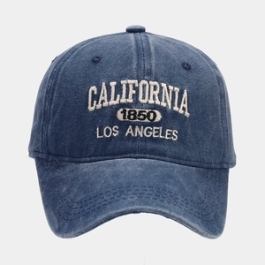 Detailed close-up of white 3D embroidery on vintage blue washed denim baseball cap