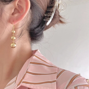 Minimalist gold ball earrings featuring three polished metal spheres in a stylish dangle drop