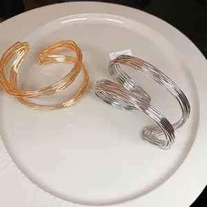 Minimalist twisted metal open cuff bracelets in polished gold and silver finish