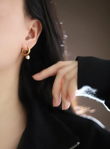 Close-up of a chic 18K gold plated hoop earring with a sparkling claw-set diamond drop