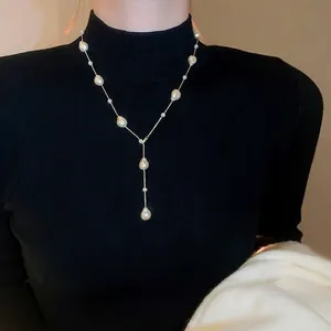 Elegant gold-plated Y-shaped pearl necklace with baroque pearls on black turtleneck sweater