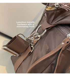 Detail of silver metal hook and D-ring on dark brown nylon tote with leather trim