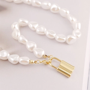 Macro shot of irregular baroque pearls with a gold-plated padlock pendant necklace