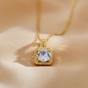 Macro shot of gold square halo pendant with brilliant round zircon on satin fabric