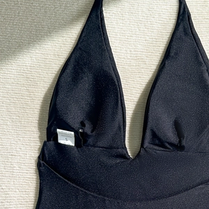 Detail of black glossy halter one-piece swimsuit with deep V-neck and size S label