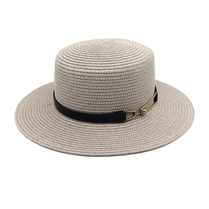 Detail view of woven straw hat featuring a sleek black leather band and gold buckle