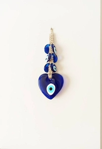 Macro view of heart-shaped blue glass evil eye wall hanging with beige rope decor