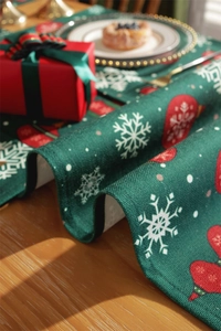 Detail of green Christmas table runner with white snowflake and red ornament patterns