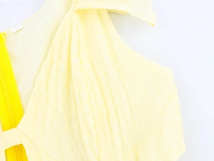 Detailed macro view of the yellow textured fabric and hidden zipper on the dress