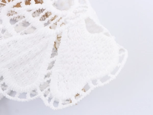 Macro detail of intricate white lace embroidery and hollowed-out texture on the shirt sleeve
