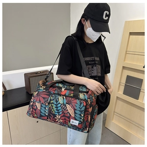 Travel tote bag featuring colorful leaf prints and adjustable straps worn by a model