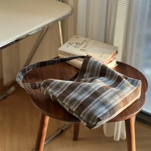 Gros plan d'un cabas en laine à carreaux sur un tabouret avec décor rétro